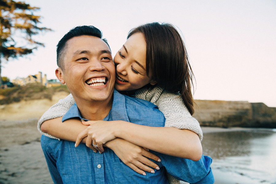 A couple in love laughing piggy backing on the beach