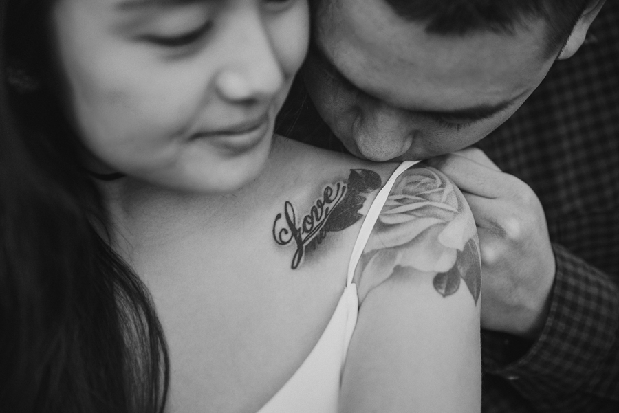 A romantic black and white image of a man kissing his fiance on the shoulder